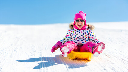 Girl smiling while sledding down snowy hill on a bright winter day  