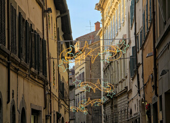 This historic Cortona alley is adorned for Christmas with suspended yellow star lights and green decorations weaving along the stone buildings