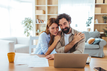 Couple at Home Working Together on Laptop, Sharing a Warm Hug and Cozy Comfort