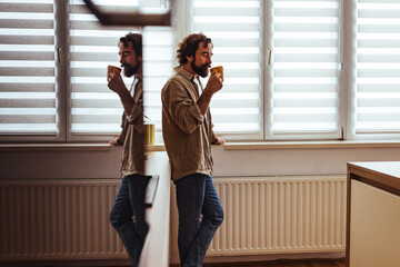 Casual Man Drinking Coffee by Window in Bright Office During Morning Break
