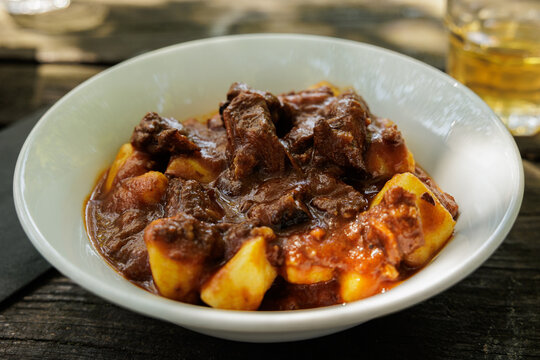 piatto di gnocchi con sugo e spezzatino di carne, su un vecchio tavolo di legno, a pranzo, in estate