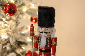 Classic nutcracker statue standing in a cozy holiday setting with a lit Christmas tree behind it.