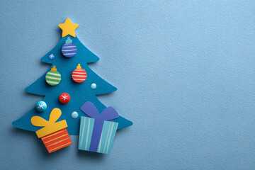 A blue vertical card design with a paper tree, vivid ornaments, and a striped gift offers a lively seasonal look.