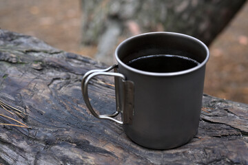 Titanium Camping Mug with Hot Drink on Tree Log Outdoors
