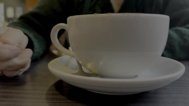 Close up of older person hands only drinking coffee from a cup. Slow motion 120fps in cafe drinking a cup of tea UK 4K