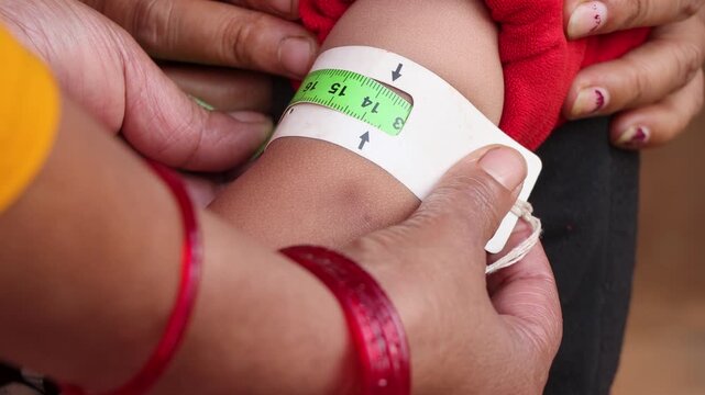 Health worker using a MUAC tape to screen a baby for malnutrition in a rural Nepal village, highlighting community healthcare and child wellness efforts in South Asia