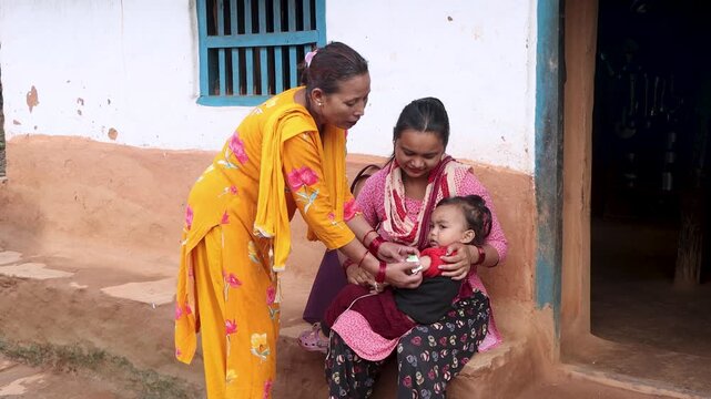 Health workers using MUAC tape to check a baby for malnutrition in a rural Nepal village, highlighting humanitarian healthcare and child wellness efforts in South Asia