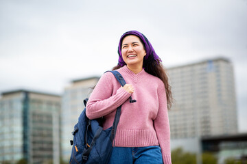 Happy Asian woman walking with backpack in cityscape background