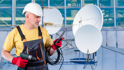 Satellite communication technician prepares tools and checks setup instructions on a tablet while servicing dish antennas and ensuring proper signal installation.