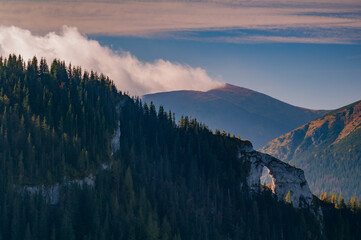 Aerial view of a stone archway nestled amidst a dense forest, with a distant mountain veiled in mist, Ohniste, Zilina Region, Slovakia.