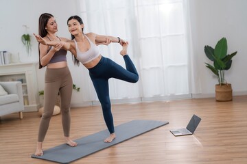 Obraz premium Two women practice yoga together in a bright room with a laptop on the floor during a morning session in their home