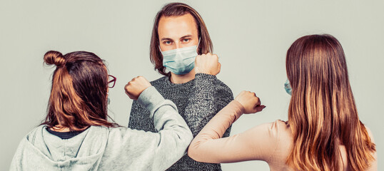 Friends wearing face mask doing new social distancing greet with elbows bumps for preventing corona virus spread - Physical distance and friendship safety greetings concept