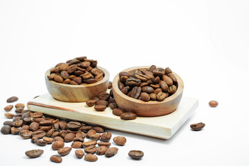 Fototapeta premium coffee beans in a rustic wooden bowl, scattered on a light wooden board and an isolated white background