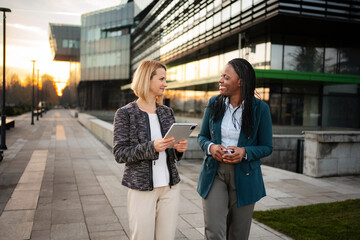 Diverse businesswomen walking and collaborating using digital tablet