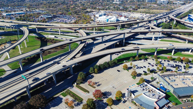 Full view modern stack interchange with retail buildings, restaurant outdoor patios near landscaped pond, active pedestrian zones and adjacent parking, vibrant mixed-use commercial hub, Plano, TX