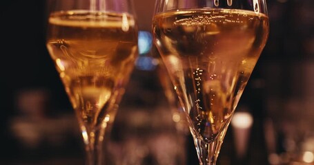 two crystal glasses standing next to each other filled with prosecco. serving alcoholic drink in restaurant. air bubbles close up in glass. foam sparkling wine. slow motion video of bubbles rising up