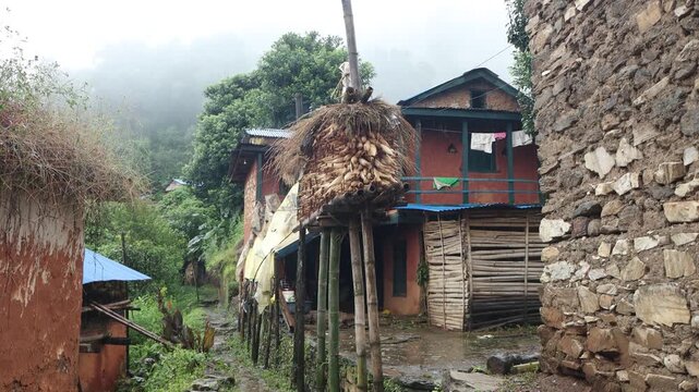 Traditional wooden house and hay storage in a rural Nepali village.