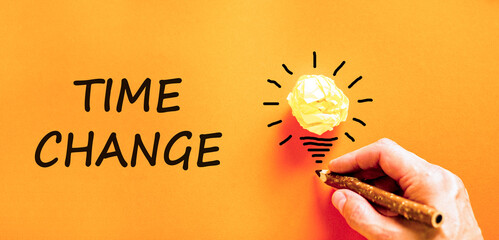 Time change symbol. Concept word Time change on beautiful orange paper. Businessman's hand. Light bulb icon. Beautiful orange paper background. Business time change concept. Copy space.