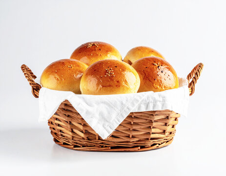 Fresh baked dinner rolls in a breadbasket, white background. AI