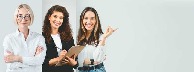 Three women stand together in a bright office space. Two women smile confidently while one takes notes on a clipboard. They exhibit teamwork and collaboration in a professional atmosphere.
