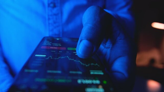 Close-up of a trader's hands buying and selling stocks online using a mobile phone application