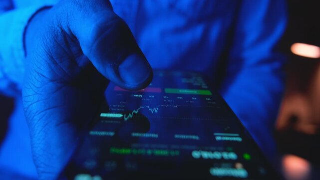 Businessman holding a phone checking stock market data, touching the screen with a blue light