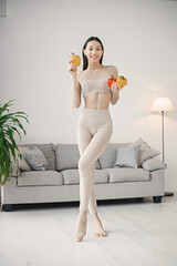 Obraz premium Young fitness woman standing at home holding red and yellow paprika