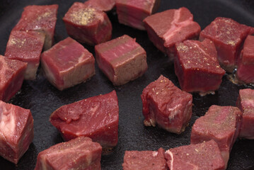 Lean beef being seared in a frying pan, cubed steak