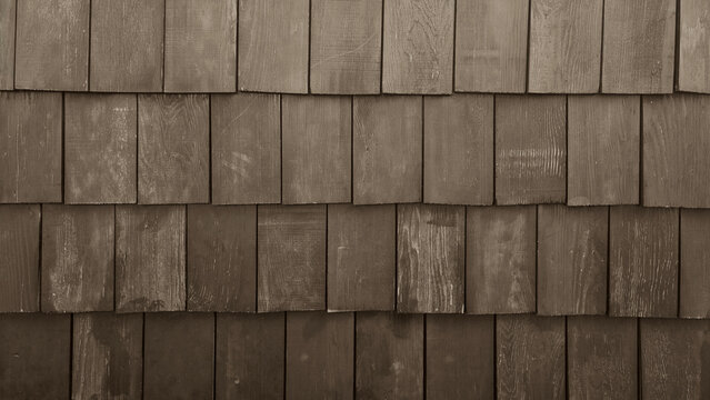 Old rustic wood shingles texture background. Brown weathered cedar shake wall siding. Grunge timber roof surface pattern with rough vertical grain details for architectural design.