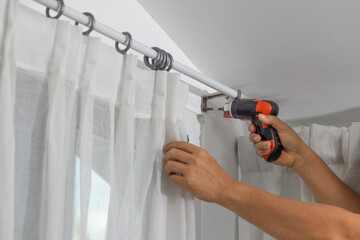 Home Improvement: Man's Hands Installing or Fixing Curtain Rod with Electric Screwdriver After...