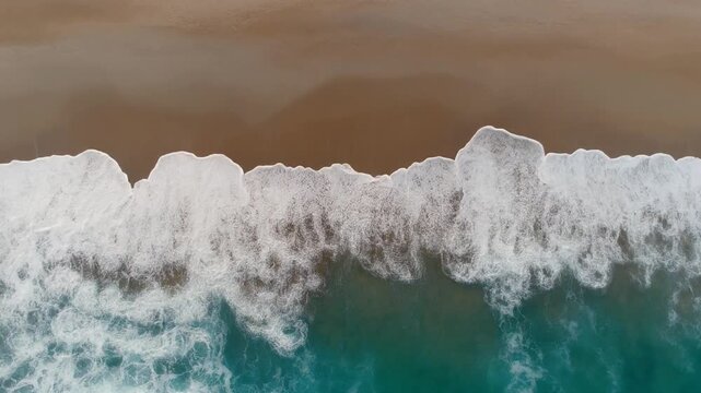 top view of  bright day half sandy beach and half ocean  with white waves