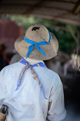 Ranch worker seen from behind wearing a worn hat and colorful bandanas, capturing authentic rural labor and traditional countryside lifestyle
