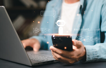 Close-up hand using a smartphone with a hologram AI chatbot virtual assistant icon. Concept of artificial intelligence, customer service, digital technology, and innovation.