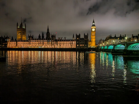 Houses of Parliament stand magnificently illuminated against the night sky, with the Elizabeth Tower (Big Ben) glowing beside the Thames.