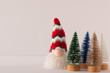 Christmas gnome with long white beard and red hat with decorating trees on white background. Holiday idea.