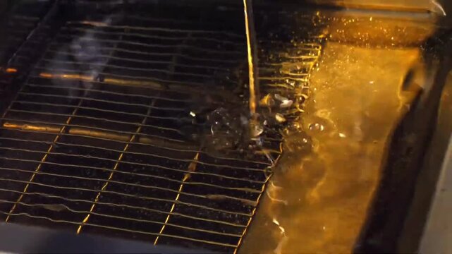 Pouring fresh golden cooking oil into a stainless steel commercial deep fryer machine
