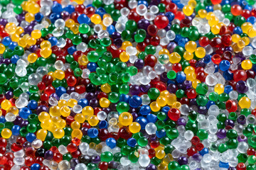 A vibrant close-up of colorful plastic pellets creates a mesmerizing backdrop. These tiny, spherical beads showcase a dynamic spectrum of hues, emphasizing their translucent nature, ideal for industri
