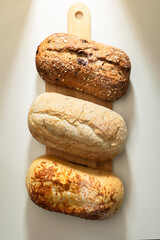 Tres panes artesanales sobre tabla de madera en fondo claro