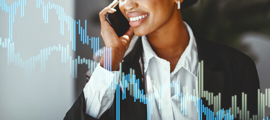In a modern office setting, a black businesswoman in formal attire smiles while enjoying a phone conversation. Her positive demeanor showcases her professional engagement during work hours.