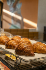Freshly baked croissants displayed on a cooling rack in a modern coffee shop