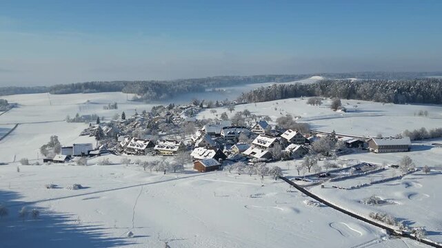 Aerial drone view of Augwil in winter with deep snow and blue sky, snow covered village and golf course