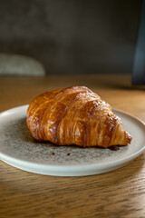 Freshly baked croissant served on a ceramic plate in warm natural light