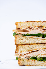 Sándwich de pavo y lechuga apilado sobre fondo blanco