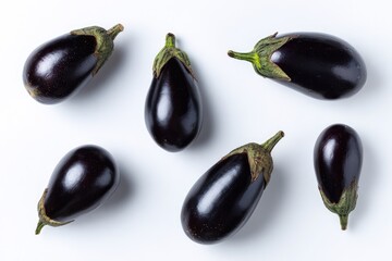 Group of shiny, dark purple eggplants with green stems scattered across a plain, white background