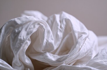 Crinkled white fabric, softly illuminated, creating a textured and abstract composition