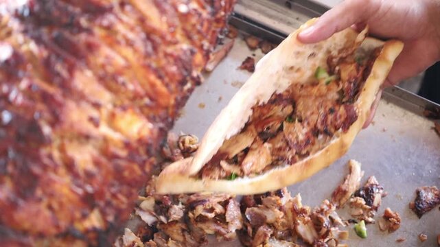 Thinly sliced, savory doner meat is generously placed into fresh bread, ready to be wrapped. Captures the final assembly of a classic street food.
