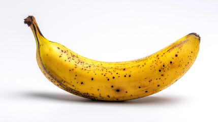 A ripe yellow banana with dark spots, lying on a clean white surface, conveys a sense of natural sweetness and ripeness.