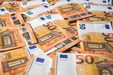 A scattered pile of fifty euro banknotes creating a textured composition that conveys wealth, finance, currency, and economic concepts.