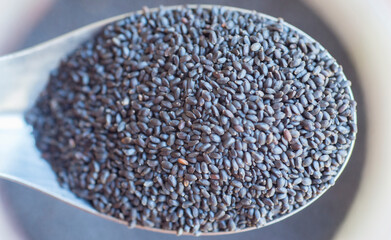 Black sesame seeds in a spoon, close-up, selective focus