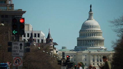 Traffic lights and signs are visible in the foreground as the US Capitol Building stands in the background in Washington DC during the day. © Robert Peak